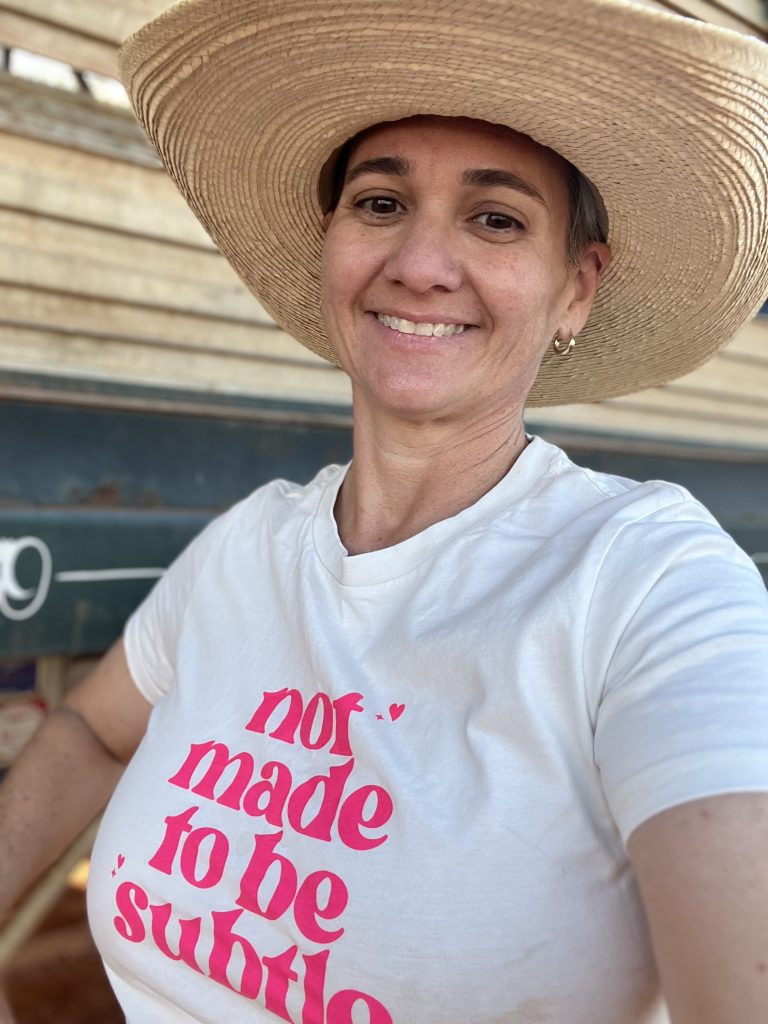 Picture of Gillian the podcast host she is wearing a cowboy hat and a tshirt that says not made to be subtle.